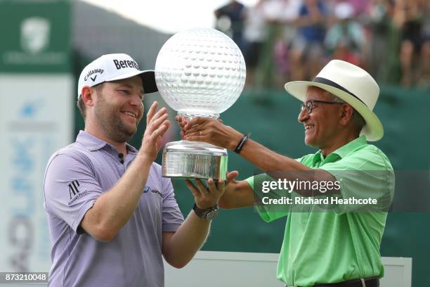 Branden Grace of South Africa is presented with the trophy by Chairman of Sun International Valli Moosa after his victory during the final round of...