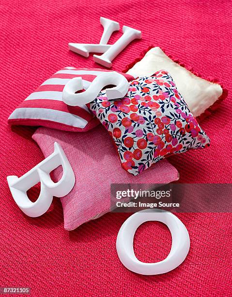 cushions and letters on a carpet - a woman modelling a trouser suit blends in with a matching background of floral print cushions stockfoto's en -beelden