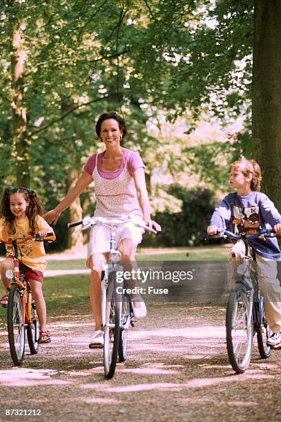 mother, doughter and son riding on bikes - doughter fotografías e imágenes de stock