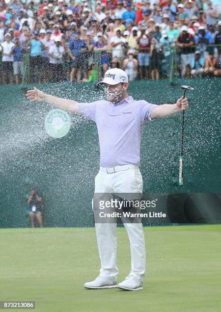 Branden Grace of South Africa is sprayed with champagne by Louis Oosthuizen and Darren Fichardt of South Africa after winning the Nedbank Golf...