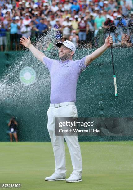 Branden Grace of South Africa is sprayed with champagne by Louis Oosthuizen and Darren Fichardt of South Africa after winning the Nedbank Golf...