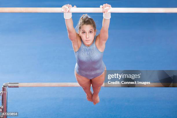gymnast hanging on uneven parallel bars - uneven bars gymnastics stock pictures, royalty-free photos & images