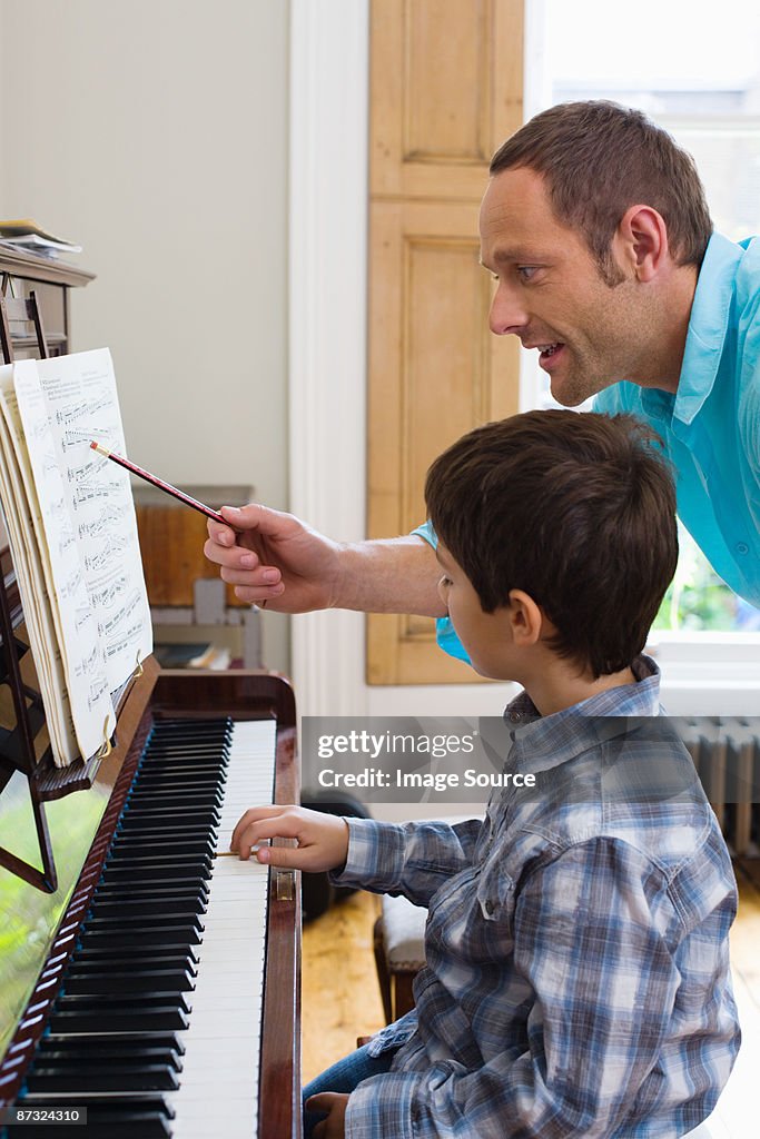 Father teaching son how to play the piano