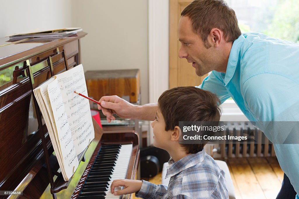 Father teaching son how to play the piano