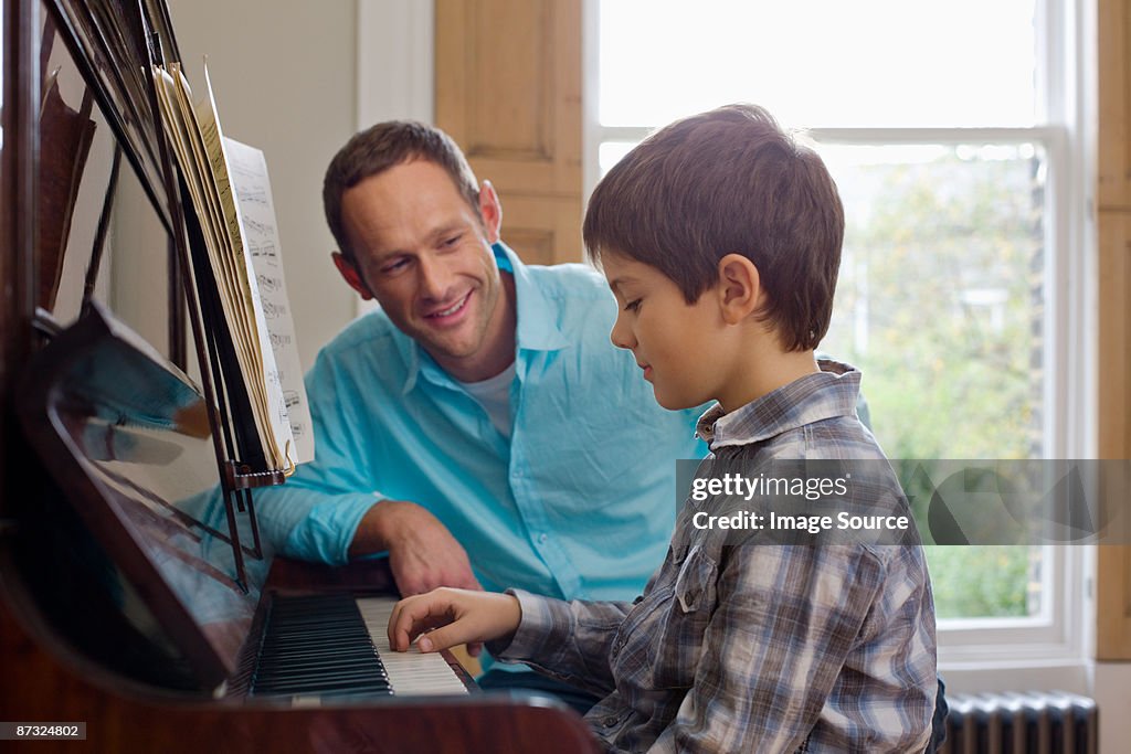 Father teaching son how to play the piano