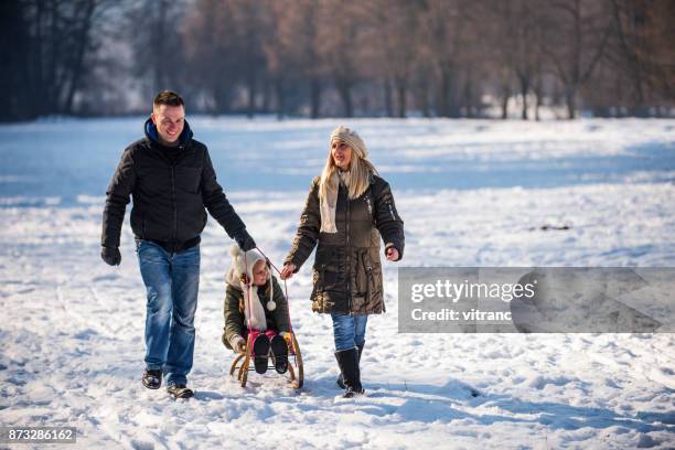 family in winter - father and mother with their daughter playing in the snow stock pictures, royalty-free photos & images