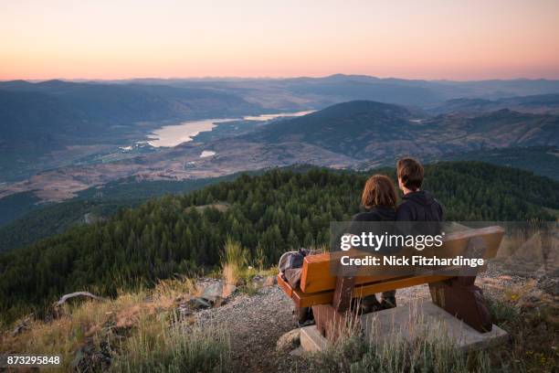 couple sitting on a bench looking at osoyoos and the south okanagan from the summit of mt kobau, british columbia, canada - okanagan valley stock-fotos und bilder