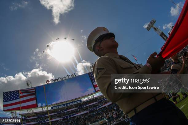 The Warbirds Flyover Team performs a flyover following the National Anthem as a serviceman holds the U.S. Flag during pregame festivities in the...