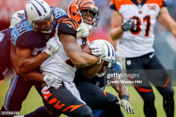 Running Back Joe Mixon of the Cincinnati Bengals carries the ball as he is defended by Linebacker Wesley Woodyard of the Tennessee Titans at Nissan...