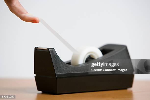 a person holding adhesive tape - tape dispenser photos et images de collection