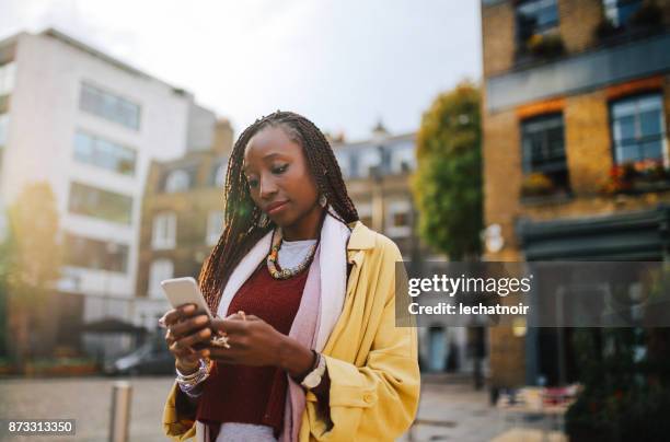 young woman texting on the street in shoreditch, london - real people serious not looking at camera not skiny stock pictures, royalty-free photos & images