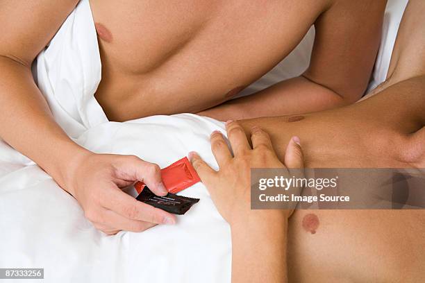 a man handing condoms to his partner - condooms stockfoto's en -beelden