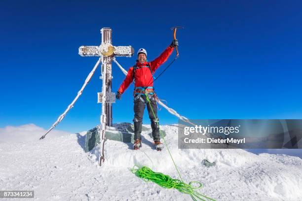 mountain climber at summit cross on top of grossglockner, austrian alps - icepick stock pictures, royalty-free photos & images