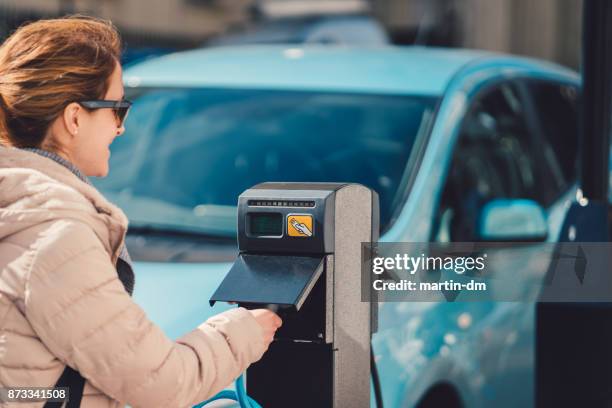 femelle à l’aide du chargeur de voiture électrique au royaume-uni - sud est de l'angleterre photos et images de collection