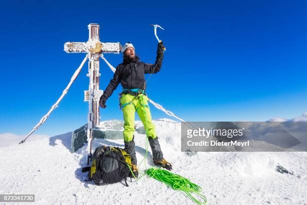 mountain climber at summit cross on top of grossglockner, austrian alps - icepick stock pictures, royalty-free photos & images