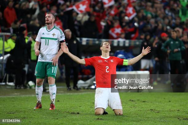 Stephan Lichsteiner of Switzerland celebrates the qualification for Russia while Chris Brunt of Northern Ireland looks down at final whistle of the...