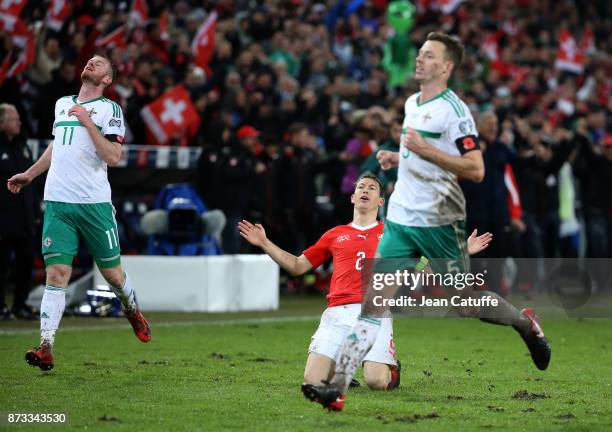 Stephan Lichsteiner of Switzerland celebrates the qualification for Russia while Chris Brunt and Jonny Evans of Northern Ireland look dejected at...