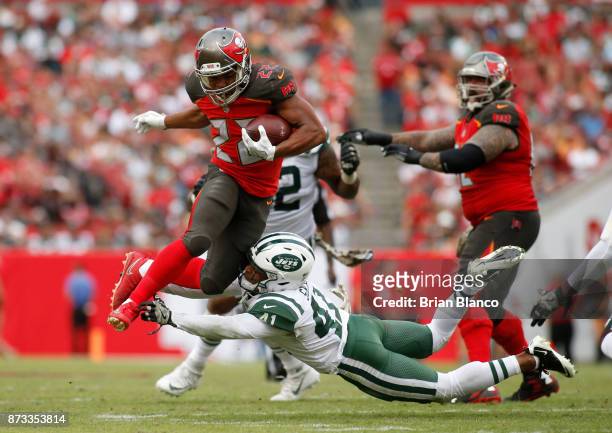 Running back Doug Martin of the Tampa Bay Buccaneers leaps over an tackle attempt by cornerback Buster Skrine of the New York Jets as he runs for a...