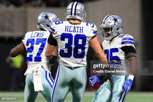 Xavier Woods celebrates an interception with Jourdan Lewis and Jeff Heath of the Dallas Cowboys during the first half against the Atlanta Falcons at...