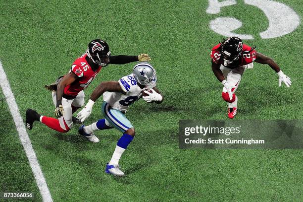 Dez Bryant of the Dallas Cowboys runs from Desmond Trufant and Deion Jones of the Atlanta Falcons after a catch during the first half at...