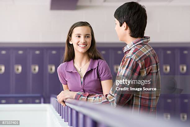teenage boy and girl talking in a corridor - boy and girl talking stock-fotos und bilder