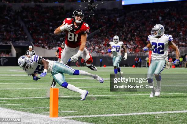 Austin Hooper of the Atlanta Falcons leaps over Xavier Woods of the Dallas Cowboys in an attempt to score a touchdown during the second half at...
