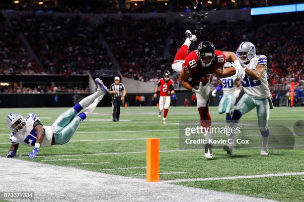 Austin Hooper of the Atlanta Falcons leaps over Xavier Woods of the Dallas Cowboys in an attempt to score a touchdown during the second half at...