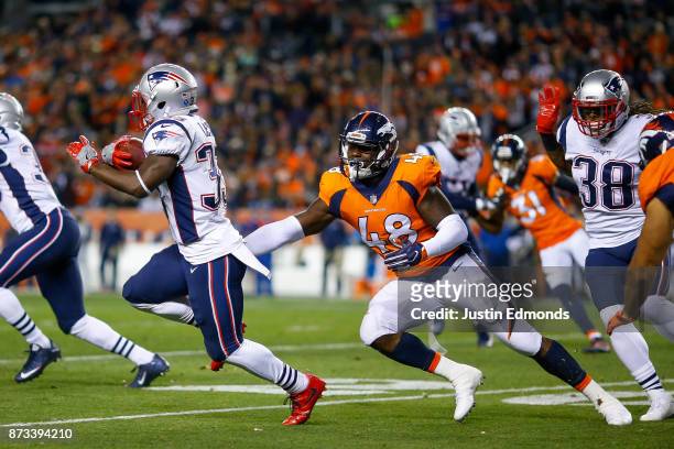 Running back Dion Lewis of the New England Patriots avoids a tackle attempt by outside linebacker Shaquil Barrett of the Denver Broncos returns a...