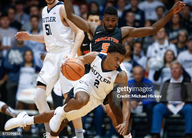 Aaron Thompson of the Butler Bulldogs trips while dribbling as Amir Bell of the Princeton Tigers defends at Hinkle Fieldhouse on November 12, 2017 in...