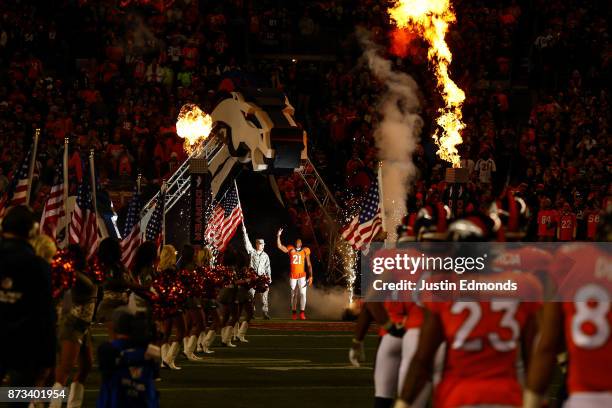 Cornerback Aqib Talib of the Denver Broncos walks onto the field next to a member of the armed forces during player introductions before a game...