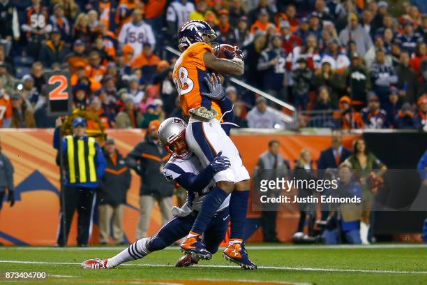 Wide receiver Demaryius Thomas of the Denver Broncos is hit by cornerback Stephon Gilmore of the New England Patriots as Thomas scores a third...