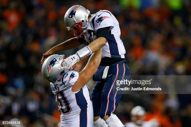 Quarterback Tom Brady of the New England Patriots is lifted by David Andrews after a fourth quarter touchdown pass against the Denver Broncos at...