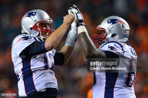 Quarterback Tom Brady of the New England Patriots celebrates a fourth quarter touchdown against the Denver Broncos with offensive guard Shaq Mason of...