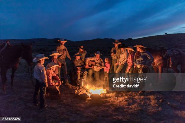 campfire singalong with cowboys and cowgirls at night - tough love stock pictures, royalty-free photos & images
