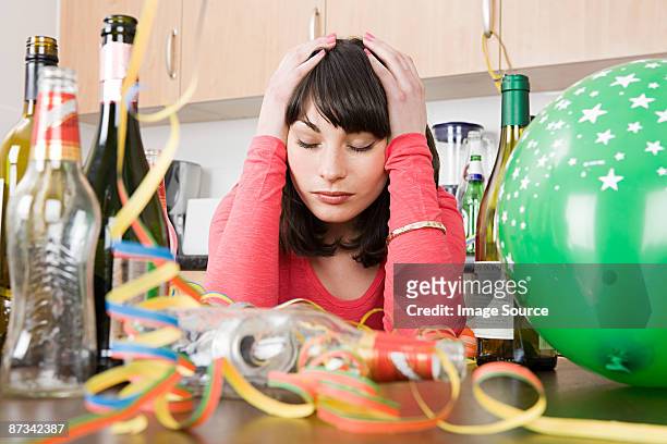 woman with a hangover after a party - messy house after party stock-fotos und bilder