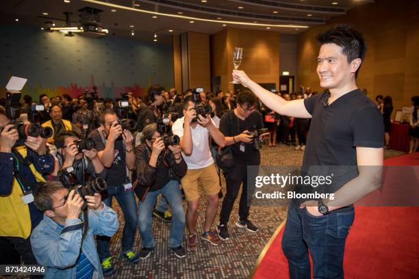 Billionaire Tan Min-Liang, chief executive officer and co-founder of Razer Inc., raises a champagne glass as he stands for photographs for members of...