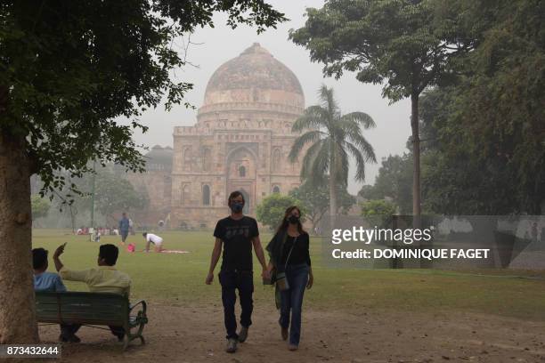 This photo taken on November 12, 2017 shows tourists visiting Lodi Gardens amid heavy smog in New Delhi. Schools reopened in New Delhi on November 13...