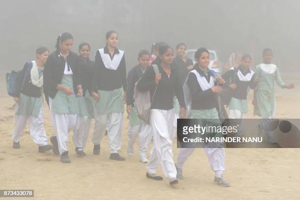 Indian schoolgirls walk to school after three days off due to heavy smog in Amritsar on November 13, 2017. Large swathes of north India and Pakistan...