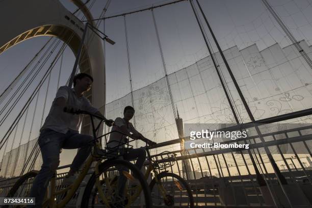 Cyclists ride Ofo Inc. Bicycles on the Liede Bridge over the Pearl River in Guangzhou, China, on Wednesday, Nov. 1, 2017. China is poised for an...
