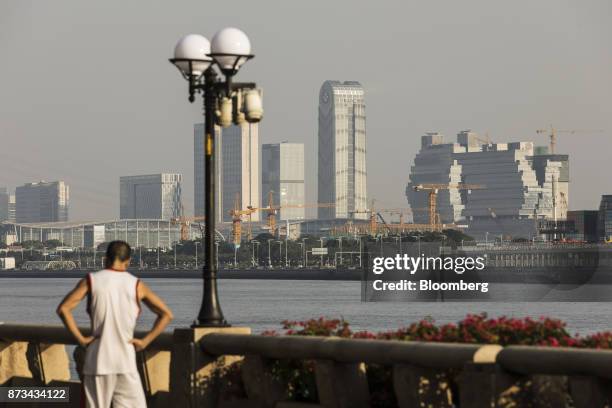 Construction cranes operate in the distance as a man pauses next to the Pearl River in Guangzhou, China, on Tuesday, Oct. 31, 2017. China is poised...