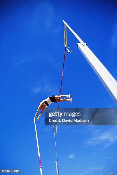 pole vaulter clearing bar, low angle view - mens pole vault stockfoto's en -beelden