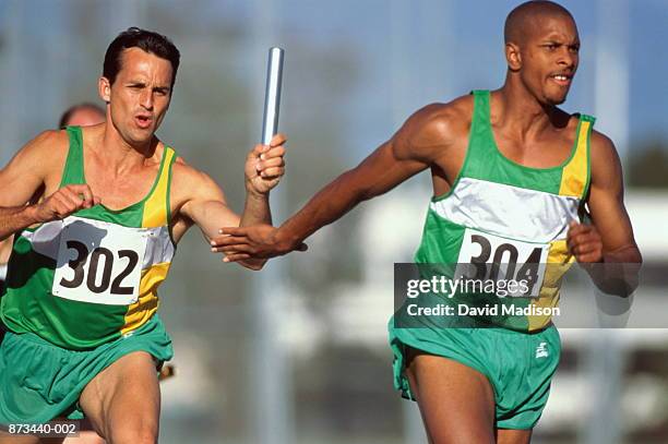 relay race, competitor passing baton to team-mate - running mate fotografías e imágenes de stock