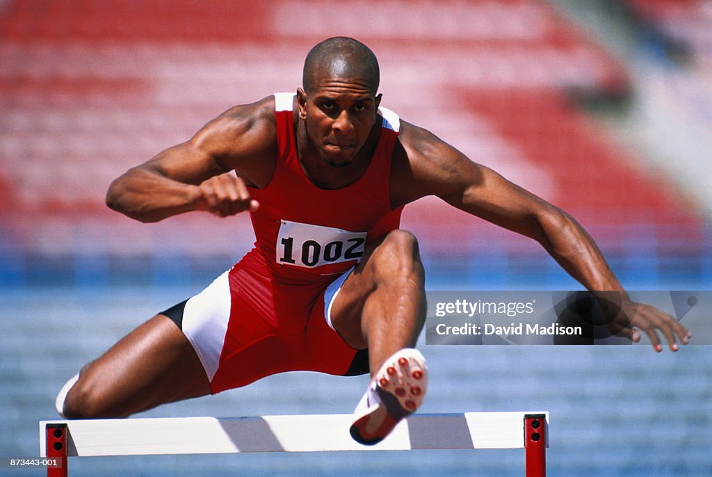 Track and Field, runner jumping over hurdle