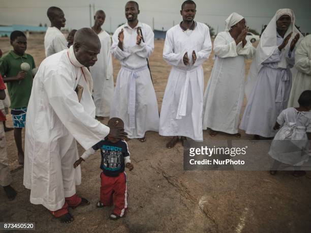 Child is prayed over by the apostolic faith leader of this church group. Apostolic Christians conduct a religious service in a piece of open land in...