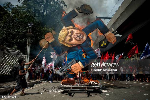 Protesters burn an image of US President Donald Trump fashioned on a swastika as they march the streets of Manila during the start of the ASEAN...