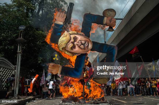 Protesters burn an image of US President Donald Trump fashioned on a swastika as they march the streets of Manila during the start of the ASEAN...