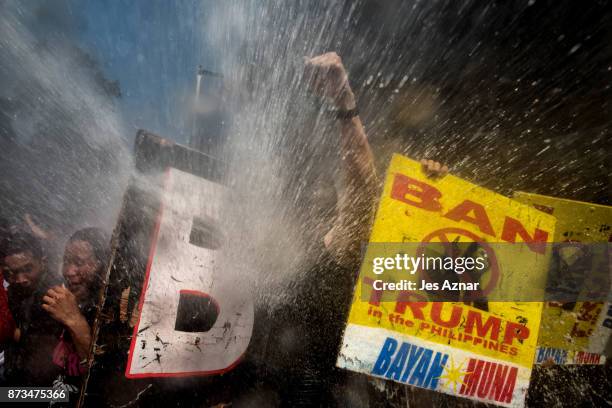 Protesters are soaked as they clash with riot police as they march the streets of Manila during the start of the ASEAN meetings between heads of...
