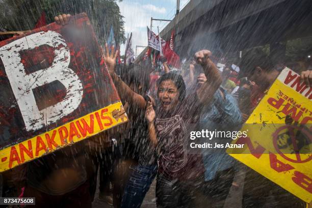 Protesters are soaked as they clash with riot police as they march the streets of Manila during the start of the ASEAN meetings between heads of...