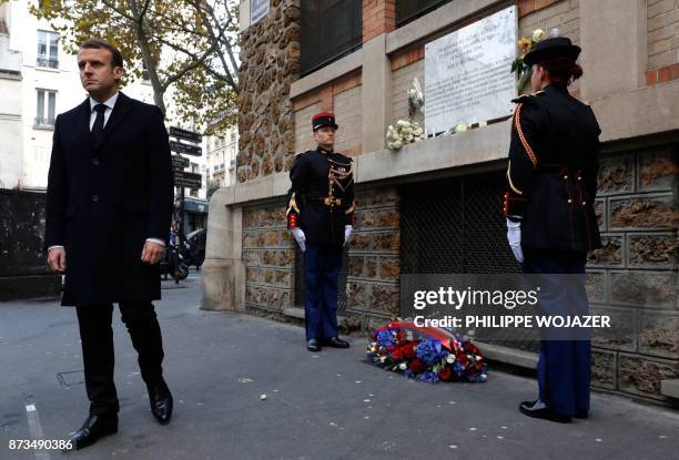 French President Emmanuel Macron looks on after laying a wreath of flowers in front of a commemorative plaque at "La Belle Equipe" bar and restaurant...