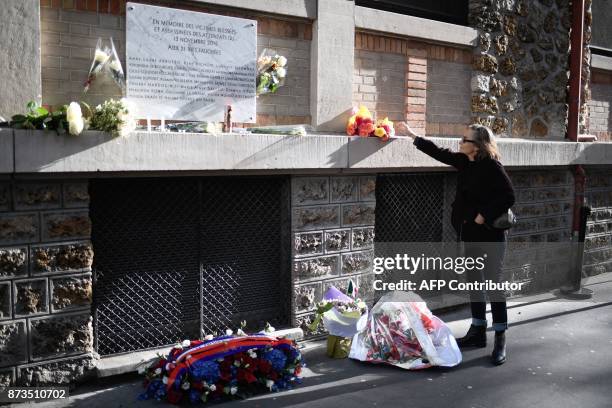 Woman lays a bunch of flowers near a plaque commemorating the victims of a shooting at La Belle Equipe cafe - restaurant during ceremonies across...
